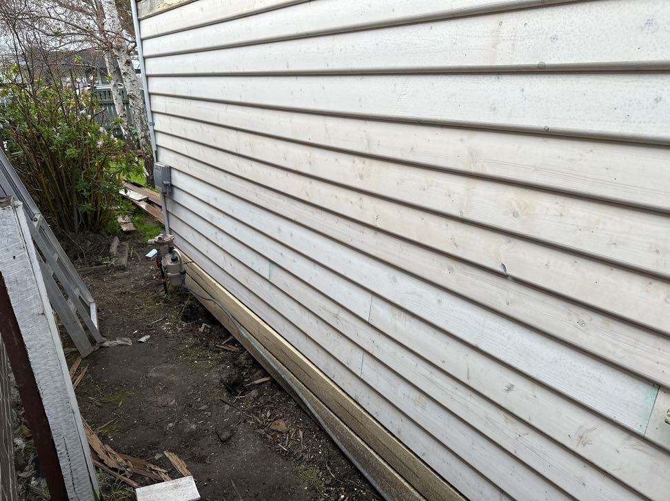 New weatherboards run down the side of the house, primed and ready to paint