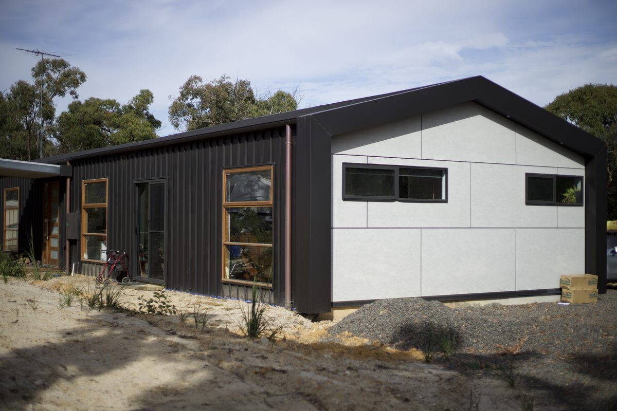 Dark metal cladding with a light fibre cement panel gable on a new building