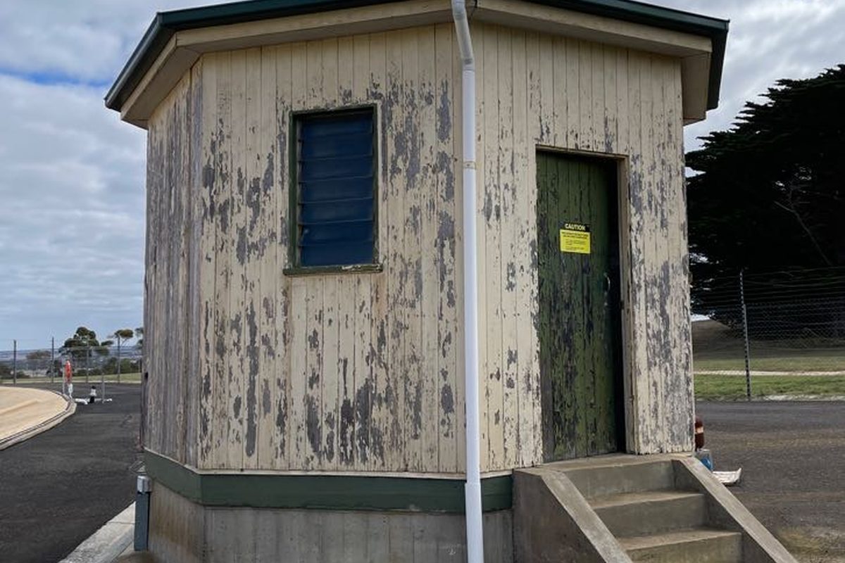 Octagonal pump building with weathered, peeling cladding before the work