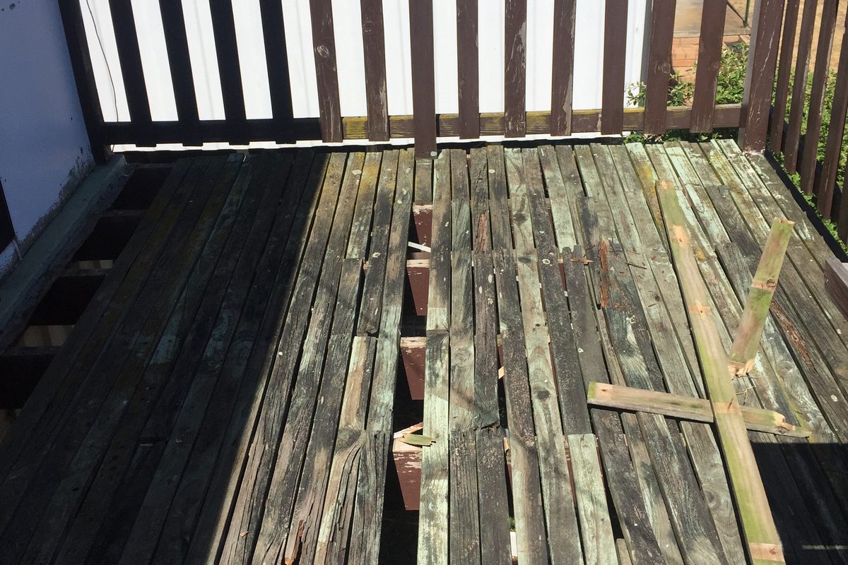 Old treated pine boards coming off a deck, with new boards going down beside them