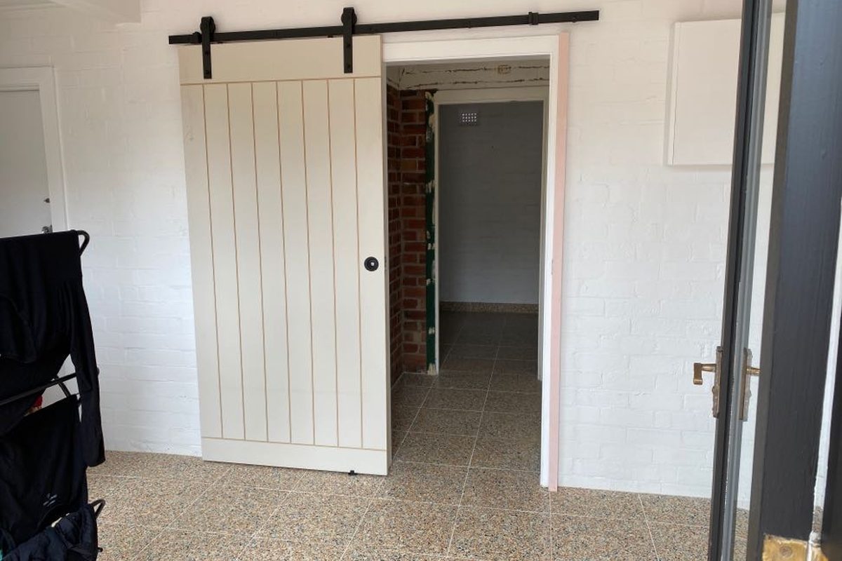 White timber barn door on a black sliding track, installed by JFM in Newtown