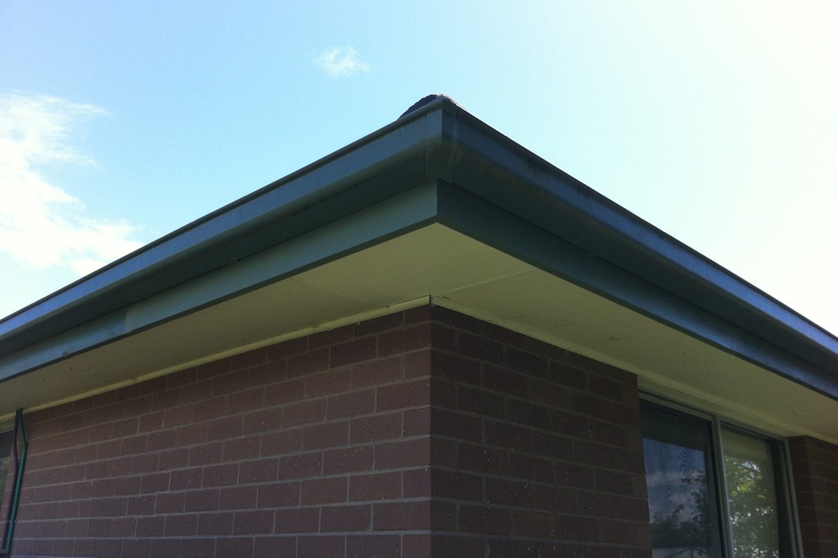 Finished fascia and eave corner, replaced and painted by JFM on a brick home