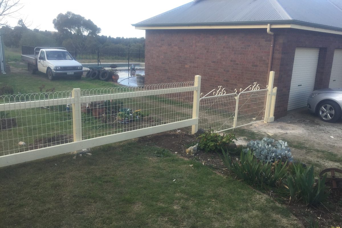 Painted post-and-rail fence with mesh around a front garden