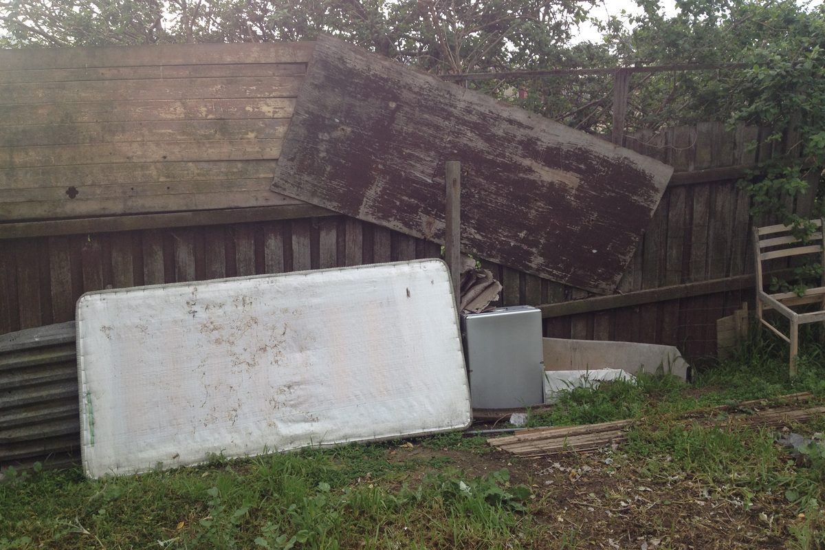 Old paling fence collapsed into a backyard before repairs