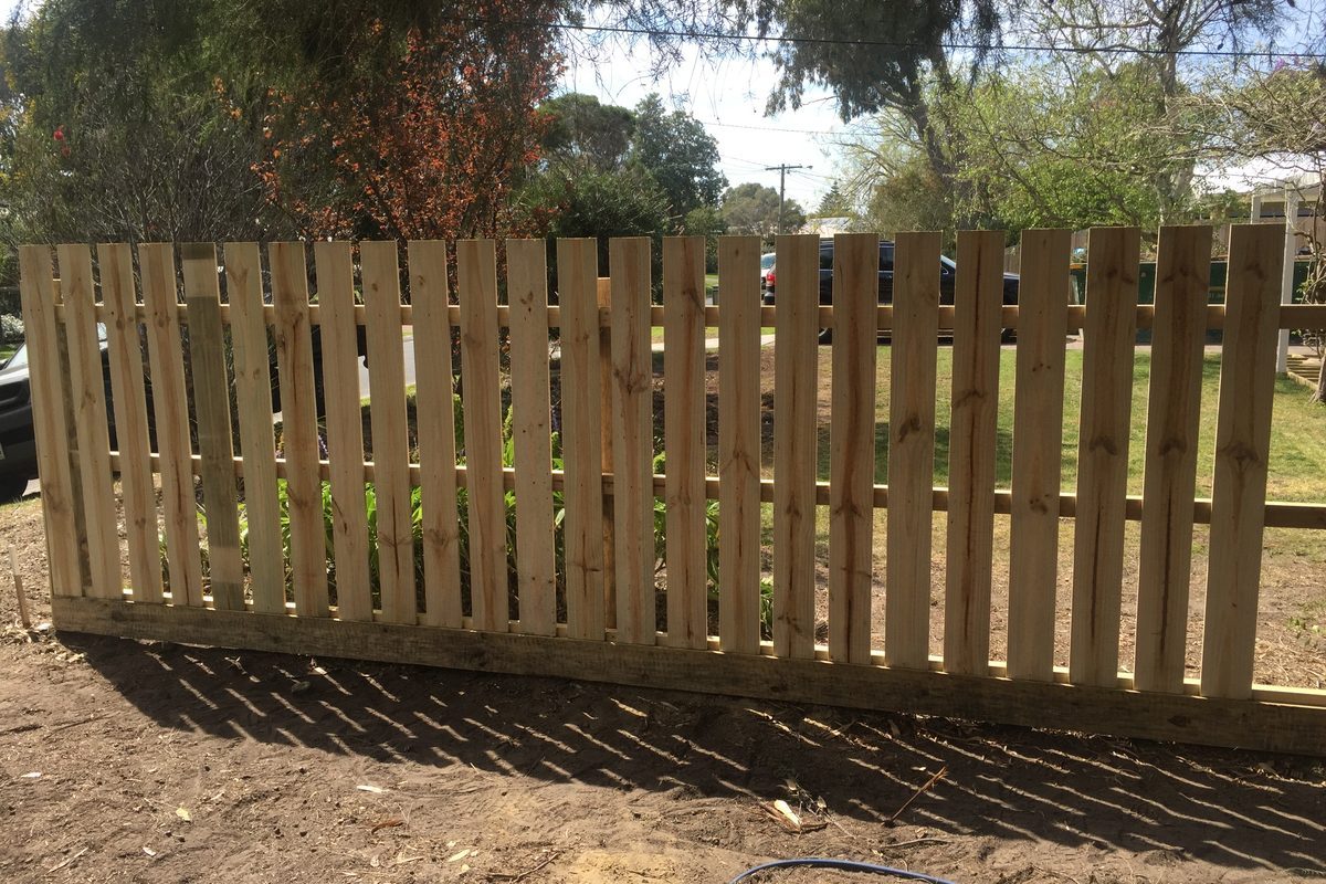 Spaced treated pine fence across the front of a house