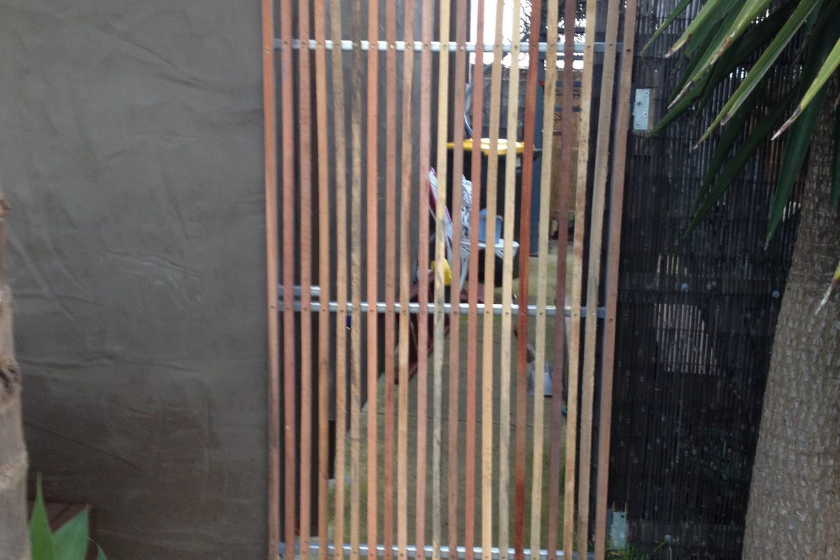 Vertical timber slat side gate down a narrow path