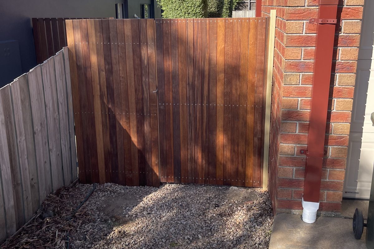 Merbau side gate and matching screen panel between a brick house and a paling fence