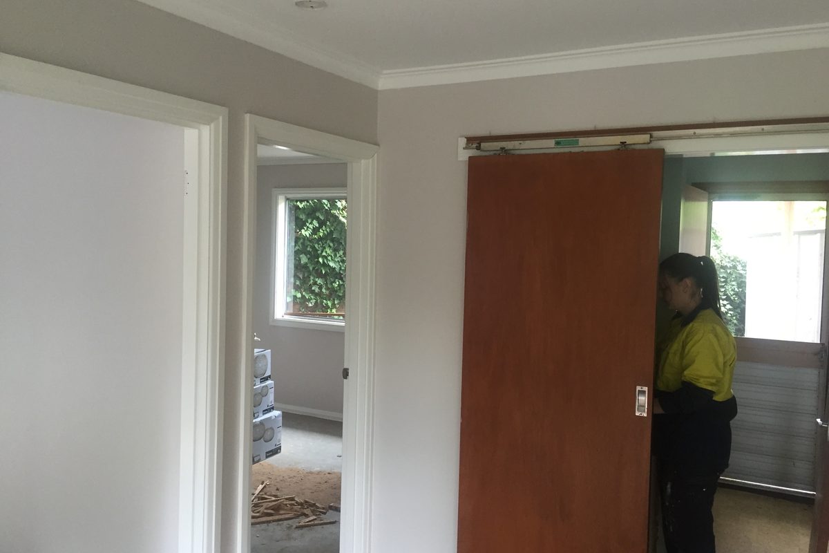 JFM carpenter hanging a sliding door in a freshly painted room