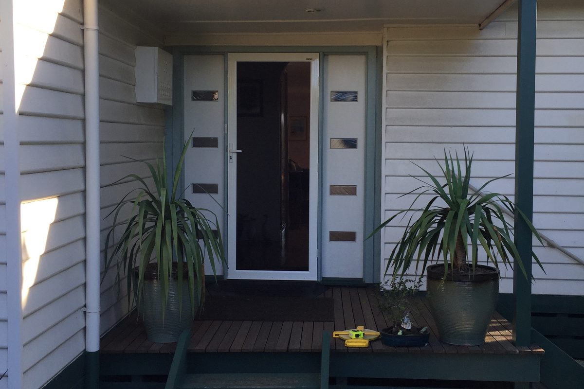 Front of a weatherboard home after repairs and a repaint by JFM