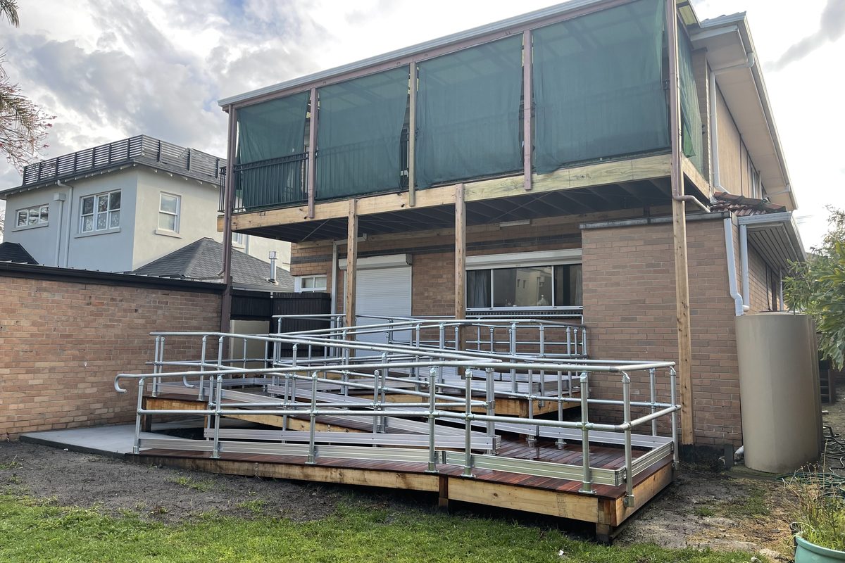 Timber wheelchair ramp with a turn, landings and galvanised handrails on both sides, built by JFM