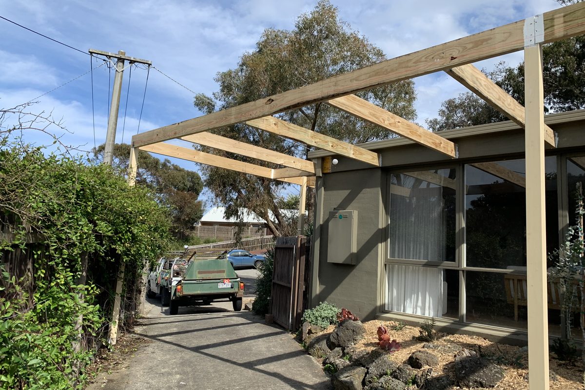 Open timber pergola running off the side of a house over the driveway, built by JFM