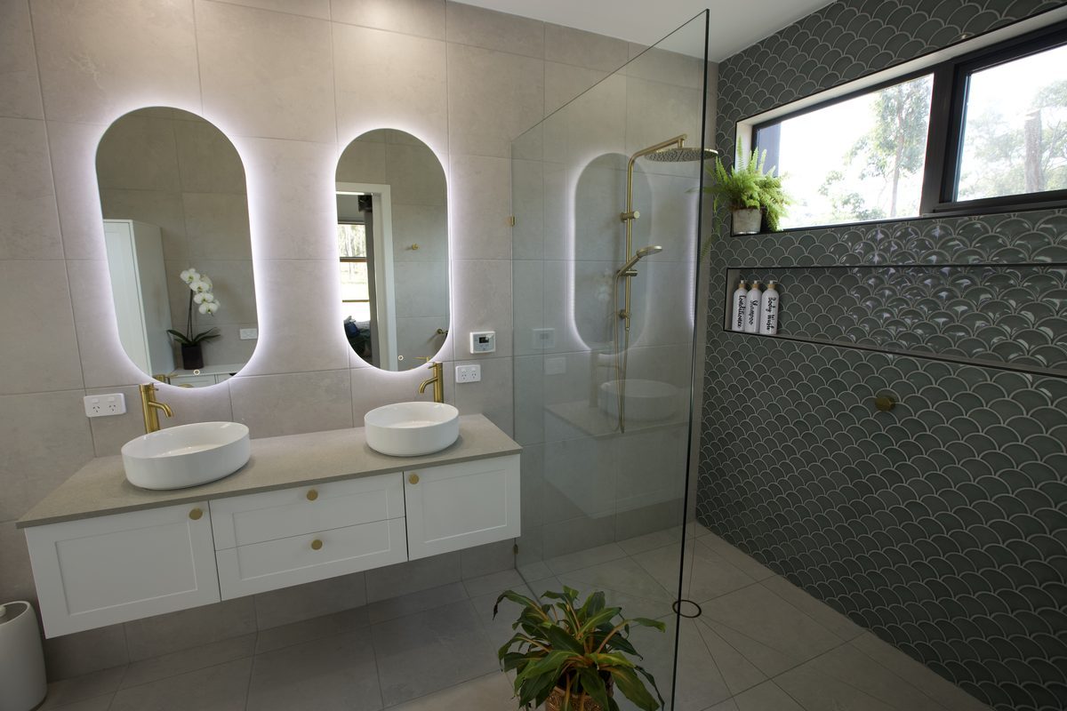 Finished bathroom with double vanity, backlit mirrors and walk-in shower