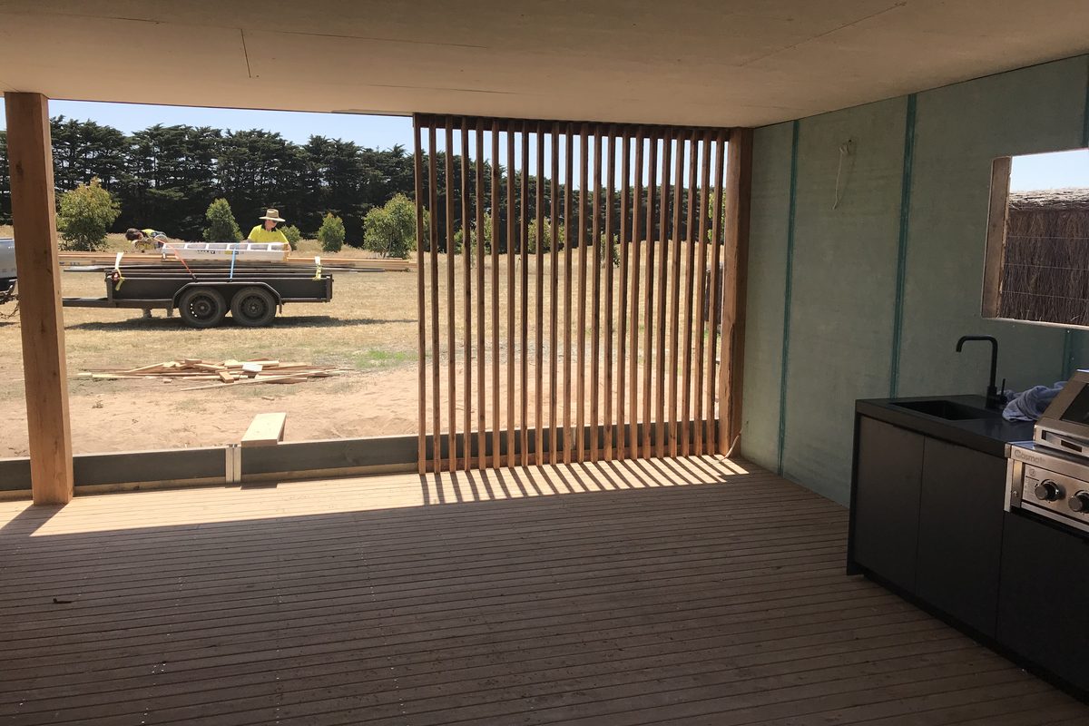 Inside the same outdoor room: decking, batten screen and outdoor kitchen