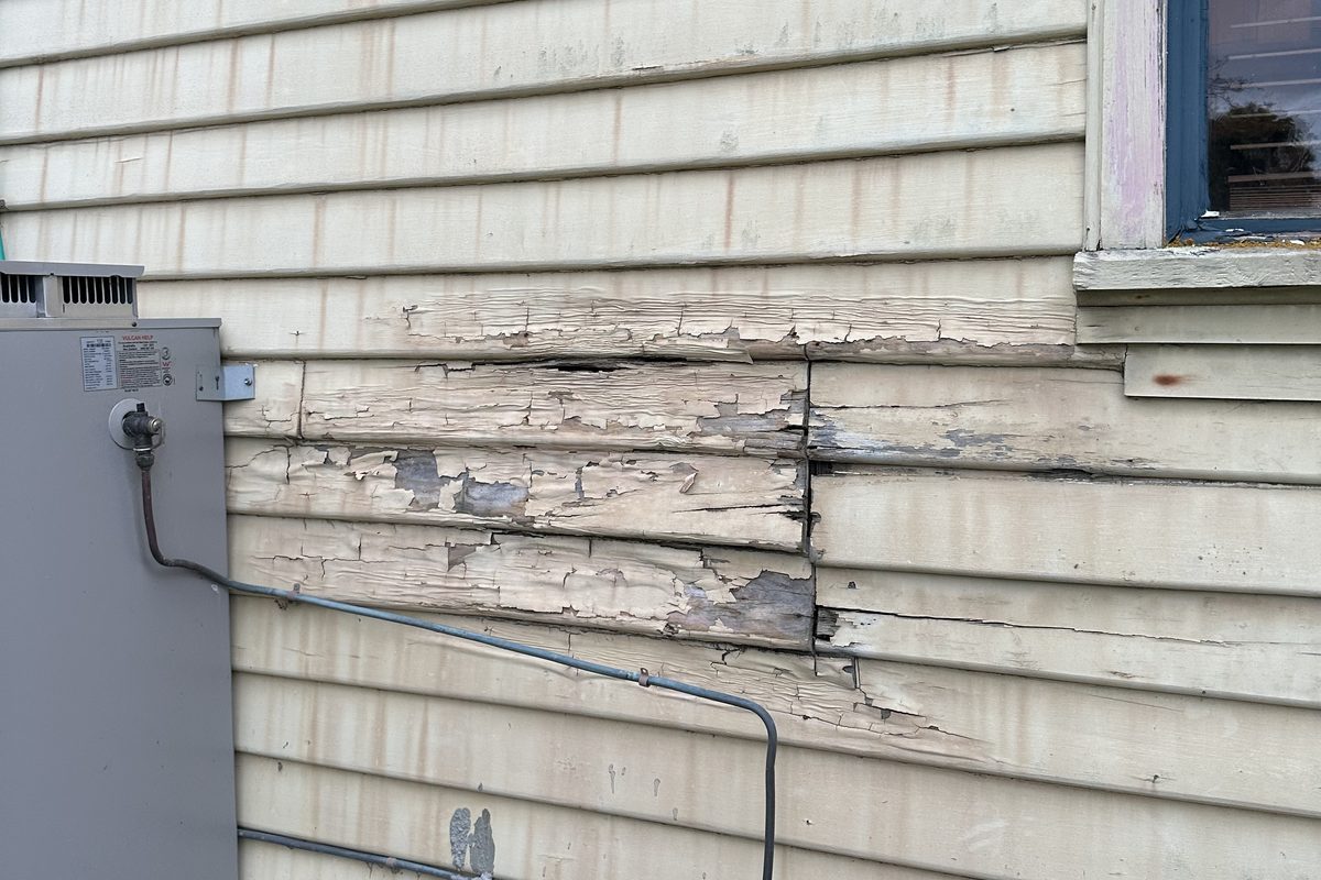 Weathered, split weatherboards on an older home before replacement